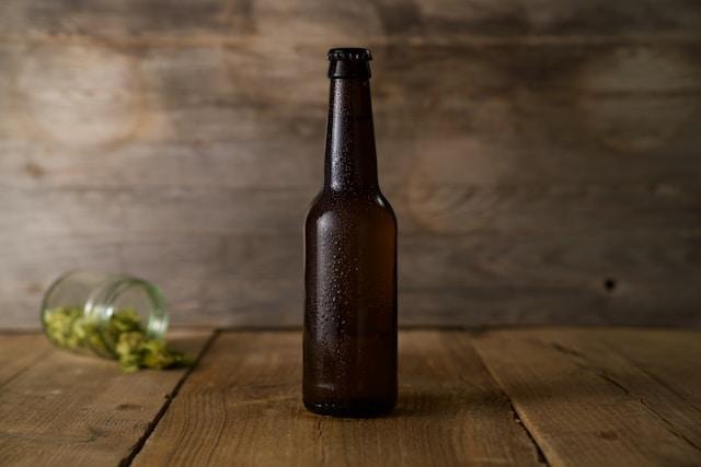 An unlabeled, perspirated beer bottle on a wooden table.